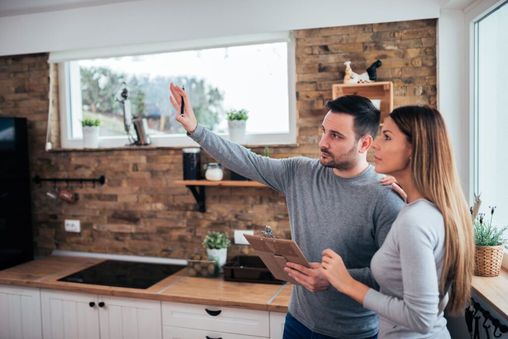 Couple in kitchen, gazing out window. Affordable home renovations, curb appeal, updates.