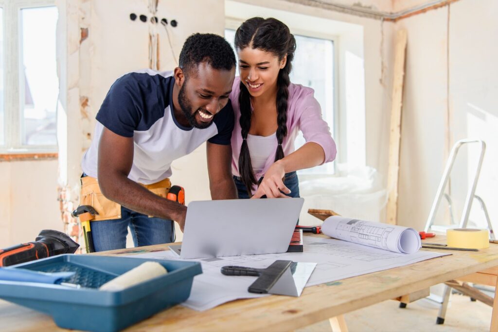 Couple on laptop in construction room. Affordable home renovations, curb appeal, affordable home updates.